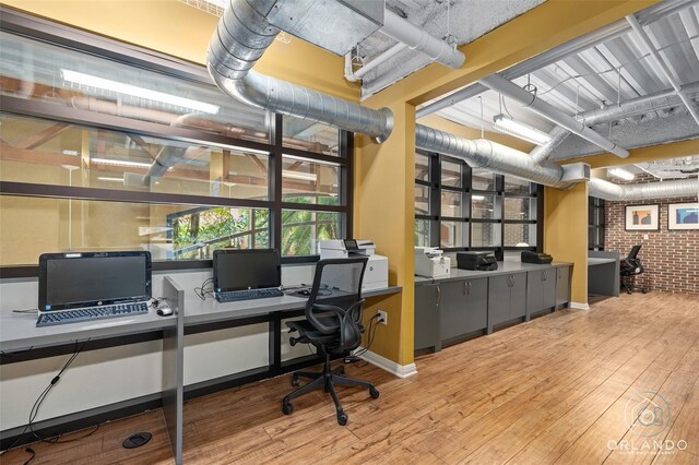 home office featuring hardwood / wood-style flooring and brick wall