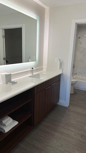 full bathroom with hardwood / wood-style flooring, vanity, toilet, and tiled shower / bath