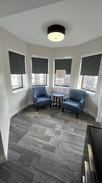 living area with a wealth of natural light and dark colored carpet