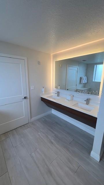 bathroom featuring hardwood / wood-style floors, double sink, large vanity, and a textured ceiling