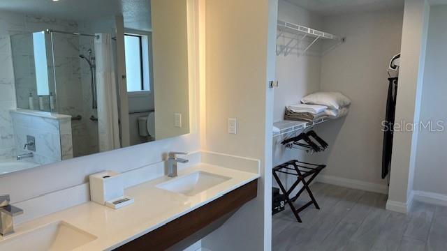 bathroom featuring wood-type flooring, an enclosed shower, and double sink vanity