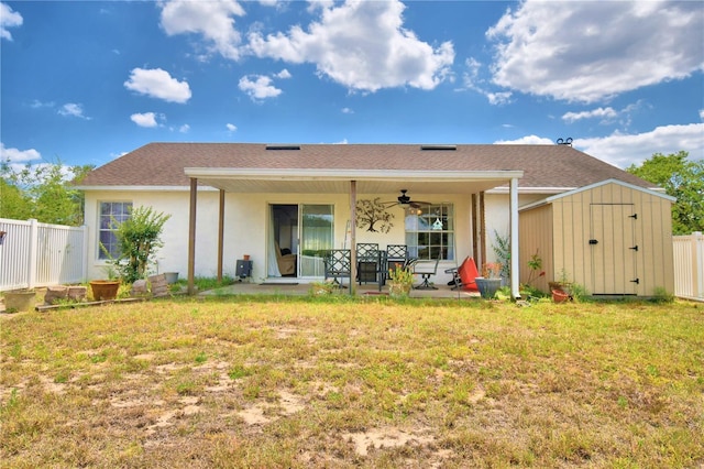 back of house featuring a yard, ceiling fan, and a storage shed