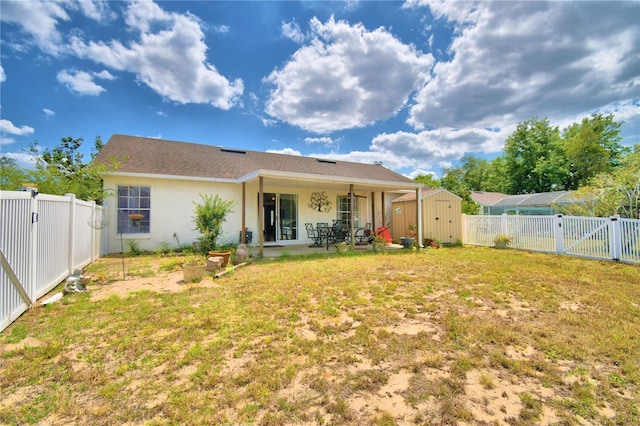 rear view of property featuring a patio area, a yard, and a storage shed