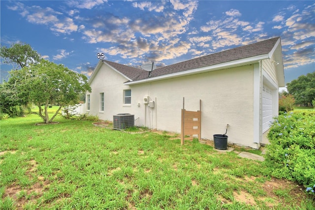 view of side of property with central AC unit and a lawn