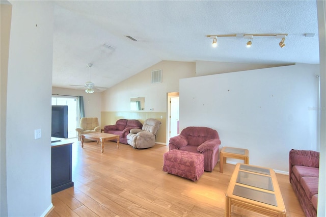 living room with a textured ceiling, light hardwood / wood-style floors, ceiling fan, and lofted ceiling