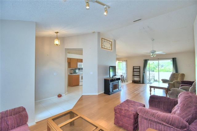 living room featuring a textured ceiling, light wood-type flooring, ceiling fan, and lofted ceiling