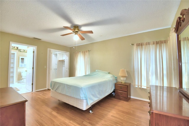 bedroom featuring ceiling fan, light wood-type flooring, a textured ceiling, and connected bathroom