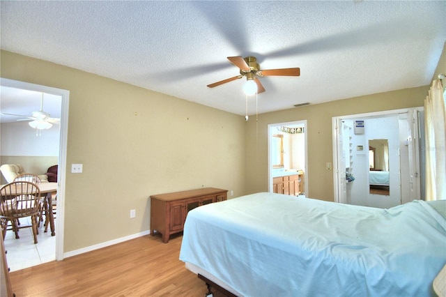 bedroom with a textured ceiling, light hardwood / wood-style floors, ensuite bath, and ceiling fan