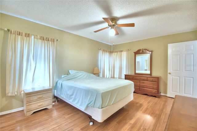 bedroom featuring light wood-type flooring, a textured ceiling, and ceiling fan