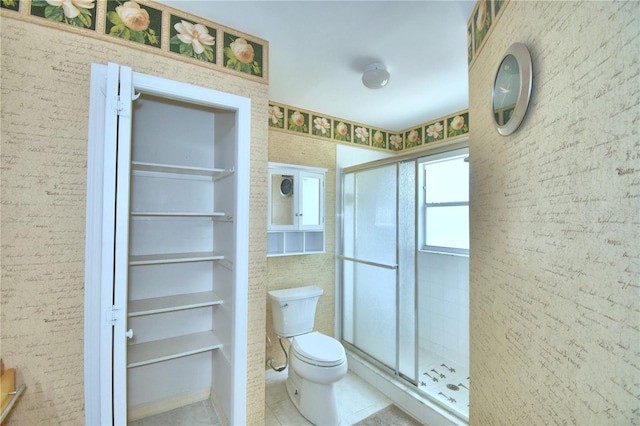 bathroom featuring tile patterned floors, a shower with shower door, and toilet