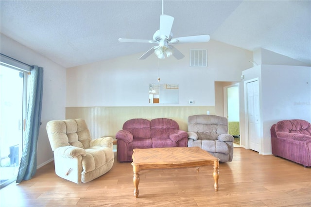 living room featuring a textured ceiling, light hardwood / wood-style flooring, vaulted ceiling, and ceiling fan