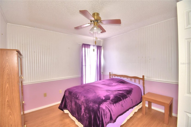 bedroom featuring a textured ceiling, hardwood / wood-style flooring, ceiling fan, and crown molding