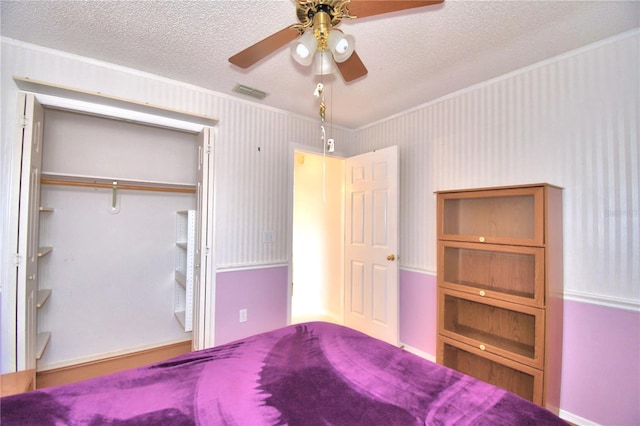 unfurnished bedroom featuring a textured ceiling, ceiling fan, crown molding, and a closet