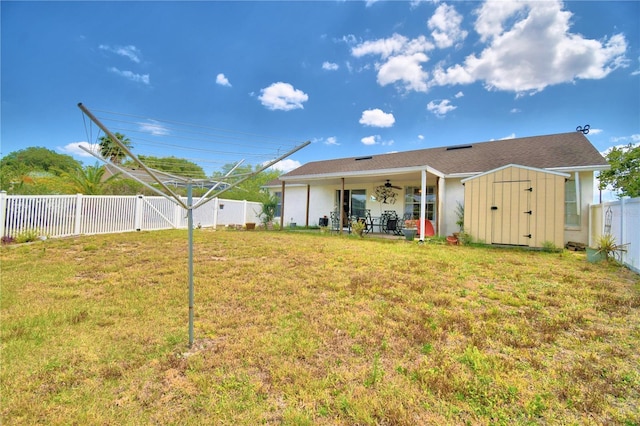 back of house featuring a yard, ceiling fan, and a storage shed