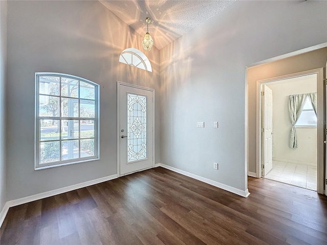 entryway featuring dark hardwood / wood-style flooring, a textured ceiling, plenty of natural light, and a notable chandelier