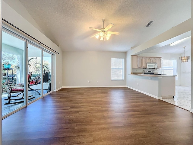 unfurnished living room featuring a textured ceiling, ceiling fan with notable chandelier, and dark wood-type flooring