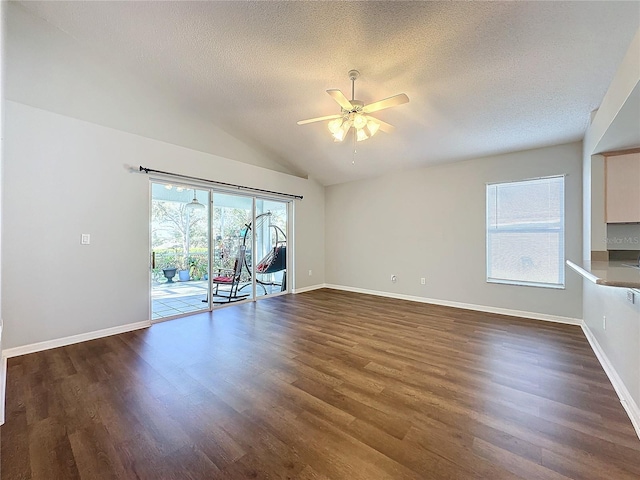 unfurnished living room with ceiling fan, dark hardwood / wood-style floors, lofted ceiling, and a textured ceiling