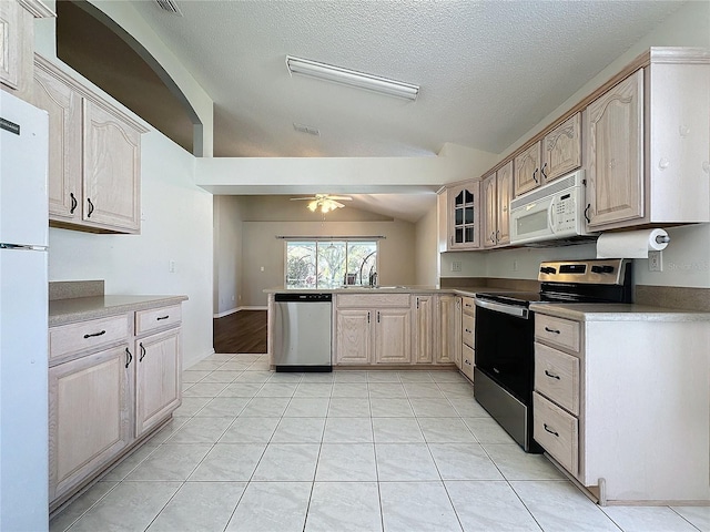 kitchen with appliances with stainless steel finishes, light brown cabinets, vaulted ceiling, and ceiling fan