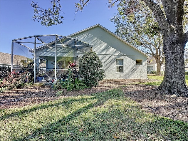 back of house featuring a lanai and a lawn