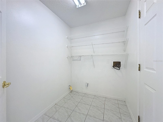 clothes washing area featuring washer hookup, a textured ceiling, and light tile patterned flooring