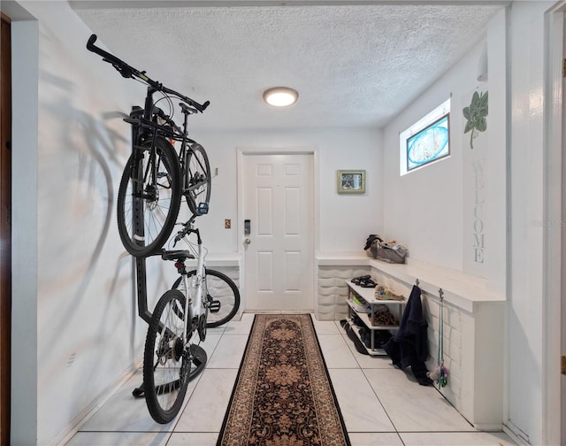 workout area featuring light tile floors and a textured ceiling