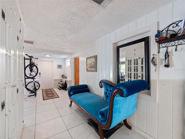 sitting room featuring a textured ceiling, french doors, and light tile floors