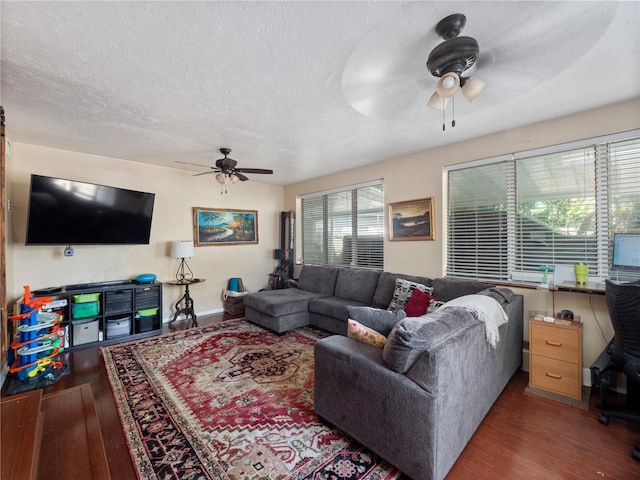 living room featuring dark hardwood / wood-style flooring, ceiling fan, and plenty of natural light