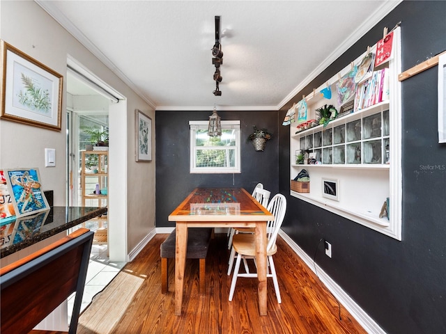 dining space with rail lighting, crown molding, wood-type flooring, and a textured ceiling