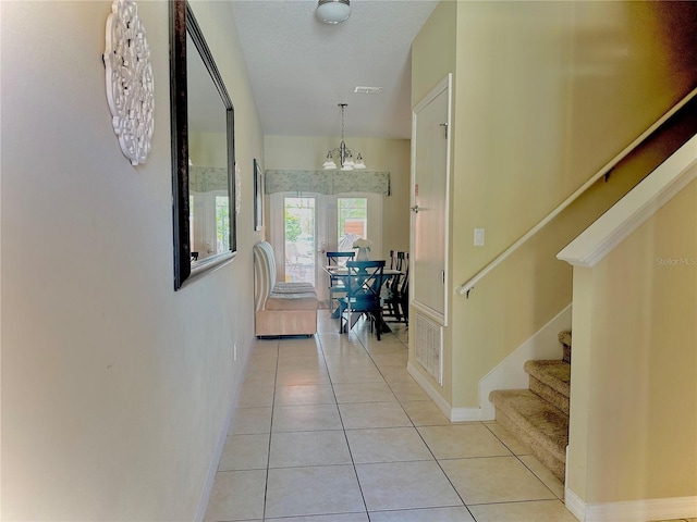 corridor with a chandelier and light tile patterned floors