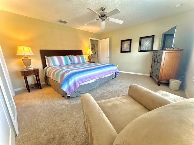 bedroom with ceiling fan, light colored carpet, and a textured ceiling