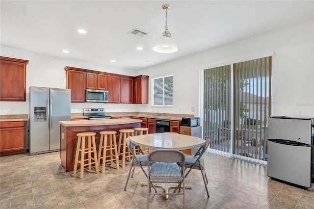 kitchen with decorative light fixtures, a wealth of natural light, black appliances, and a breakfast bar