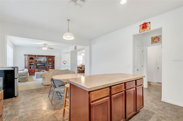 kitchen with ceiling fan, decorative light fixtures, a kitchen island, and a wealth of natural light