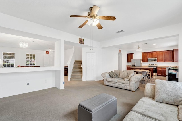 carpeted living room with ceiling fan with notable chandelier