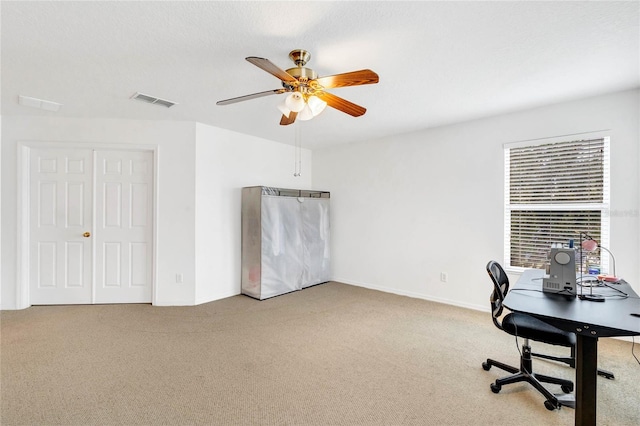 carpeted office space featuring ceiling fan