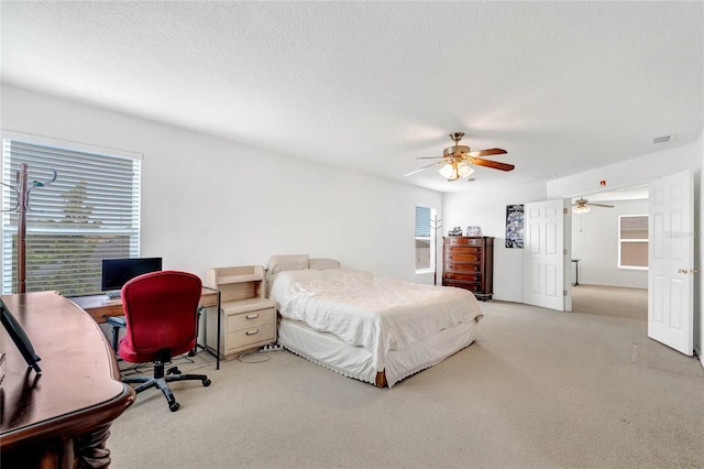 bedroom with ceiling fan, light carpet, and a textured ceiling