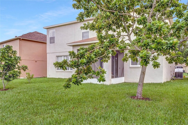 rear view of house with central AC unit and a lawn