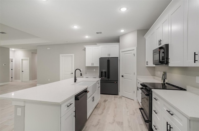 kitchen featuring black appliances, light hardwood / wood-style floors, white cabinetry, and an island with sink