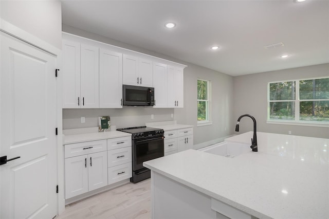 kitchen featuring white cabinets, sink, a healthy amount of sunlight, and black appliances