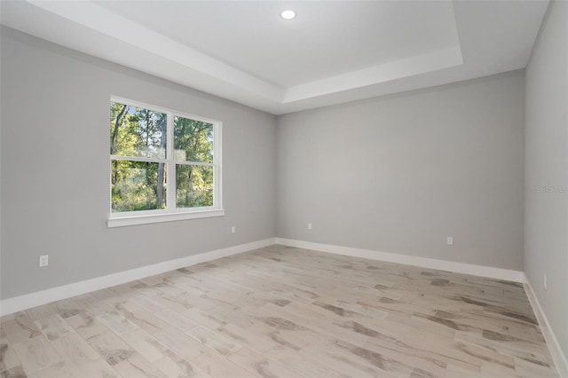 unfurnished room featuring light hardwood / wood-style flooring and a tray ceiling