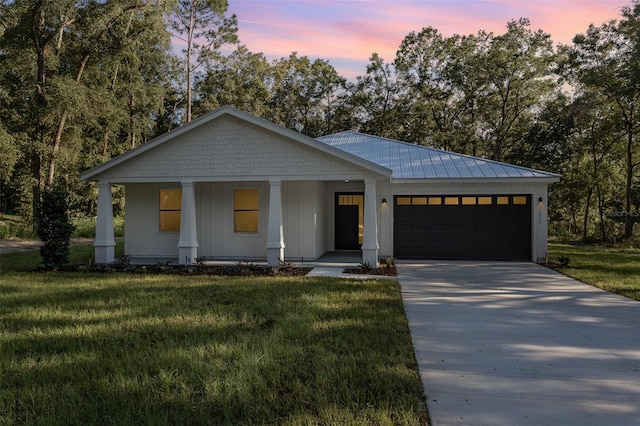 view of front of home featuring a garage, a lawn, and covered porch