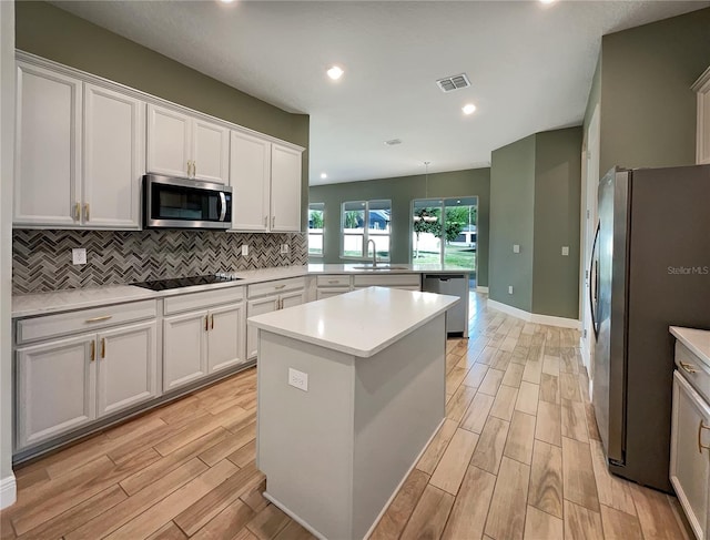 kitchen with a kitchen island, tasteful backsplash, stainless steel appliances, and white cabinetry