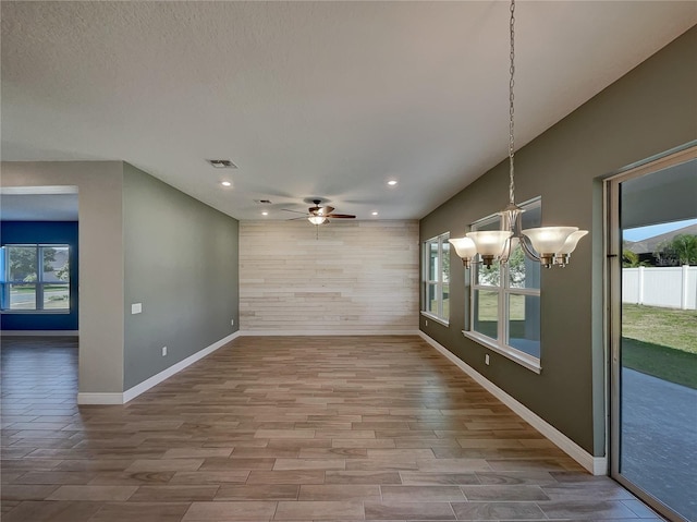 unfurnished room featuring ceiling fan with notable chandelier and hardwood / wood-style floors