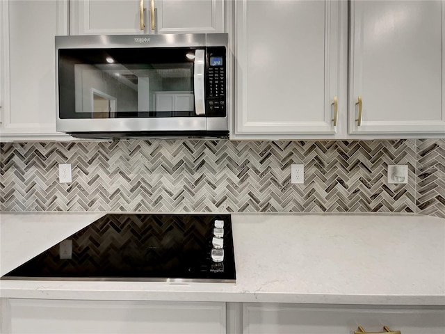 kitchen featuring white cabinets, backsplash, and light stone counters