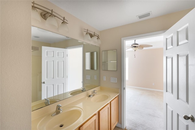 bathroom featuring dual sinks, ceiling fan, and vanity with extensive cabinet space