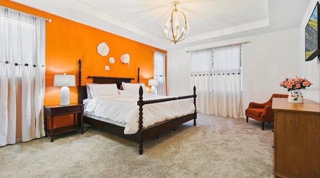 carpeted bedroom featuring a chandelier and a tray ceiling