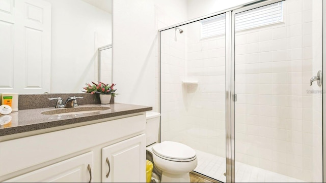 bathroom with an enclosed shower, vanity, and toilet