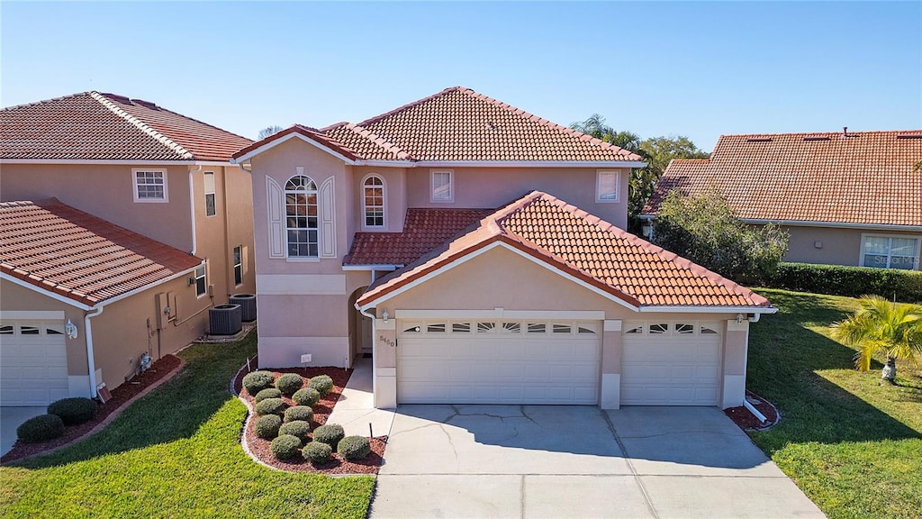 mediterranean / spanish home with central AC, a front lawn, and a garage