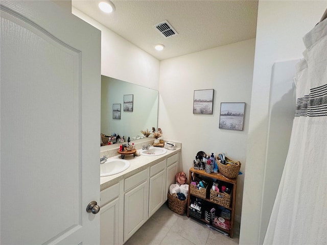 bathroom with tile flooring, vanity with extensive cabinet space, and double sink