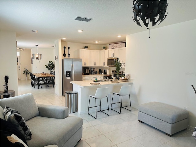 living room with sink, an inviting chandelier, and light tile floors