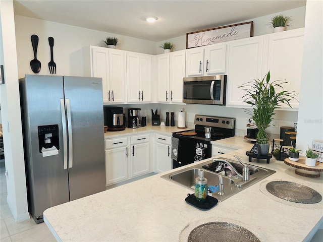 kitchen featuring white cabinets, sink, light tile flooring, stainless steel appliances, and kitchen peninsula